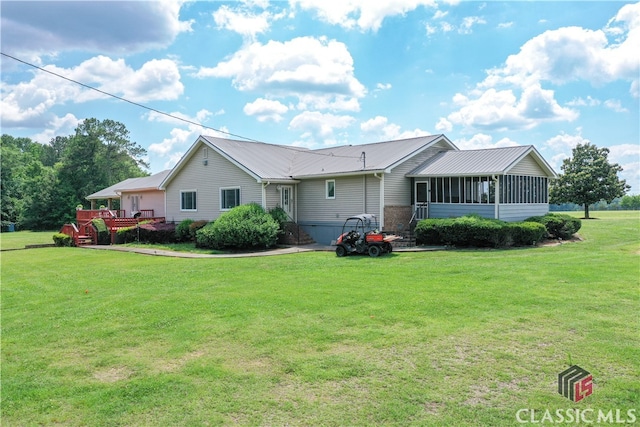 ranch-style home with a deck, a front yard, and a sunroom