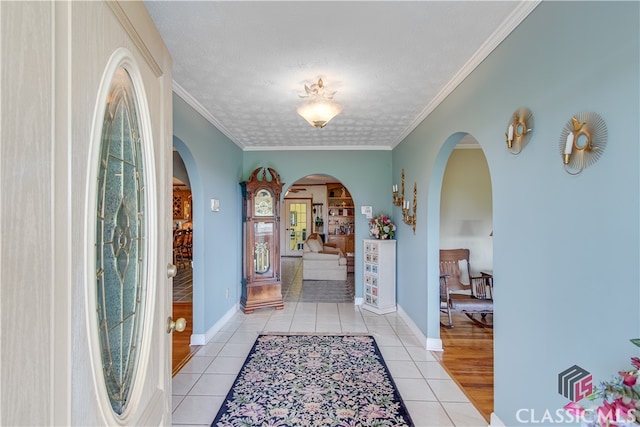 tiled entryway featuring crown molding and a textured ceiling