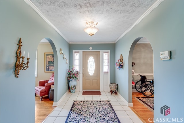 entrance foyer featuring ornamental molding, a textured ceiling, and light wood-type flooring