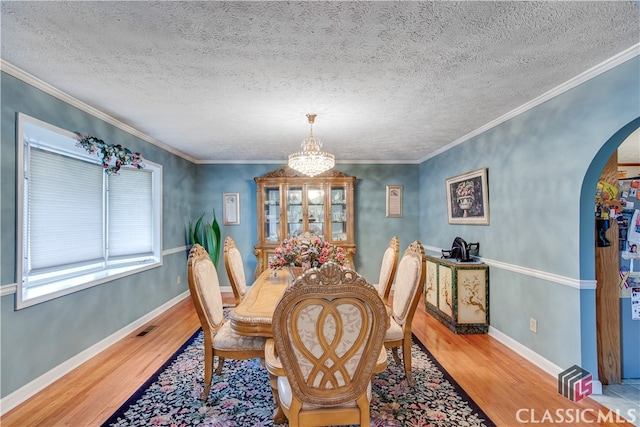 dining room featuring crown molding, hardwood / wood-style flooring, a chandelier, and a textured ceiling