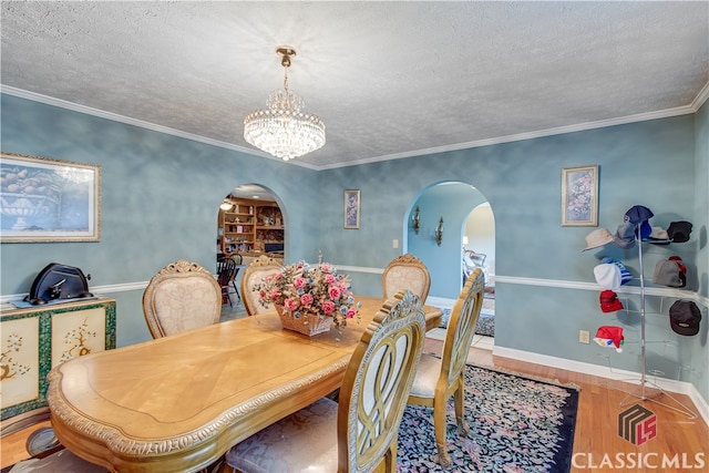 dining area featuring a notable chandelier, hardwood / wood-style flooring, crown molding, and a textured ceiling