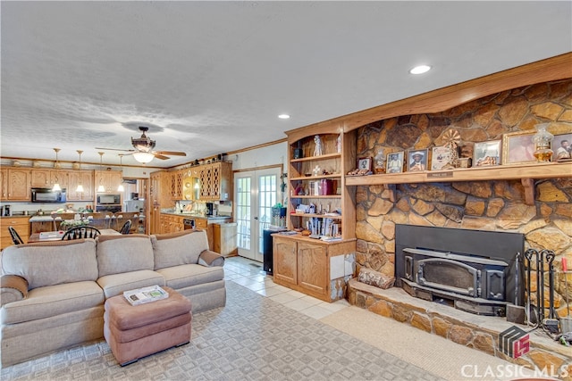 living room featuring a wood stove, a fireplace, ceiling fan, ornamental molding, and light tile floors