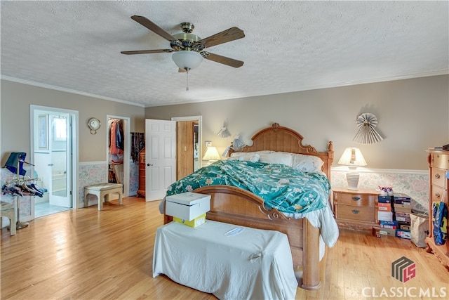 bedroom featuring ensuite bathroom, ceiling fan, light wood-type flooring, and a walk in closet