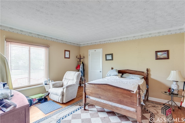 bedroom featuring ornamental molding, light hardwood / wood-style flooring, and a textured ceiling