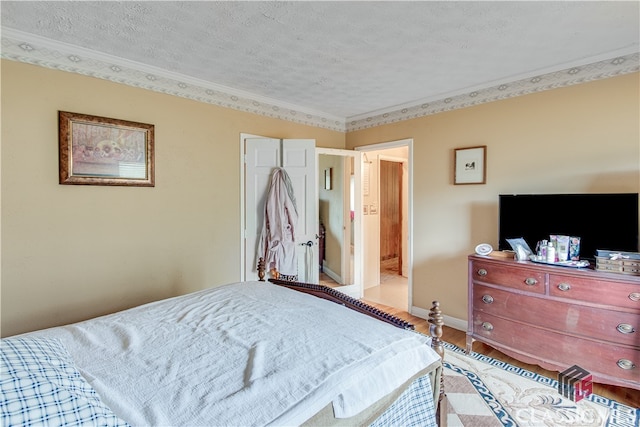 bedroom with light hardwood / wood-style floors, a textured ceiling, and crown molding