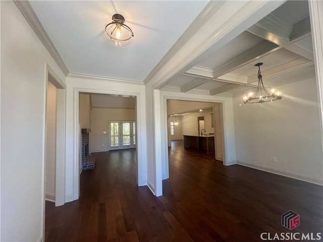 hall with dark hardwood / wood-style flooring, an inviting chandelier, ornamental molding, beamed ceiling, and coffered ceiling