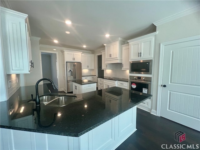 kitchen with dark hardwood / wood-style flooring, appliances with stainless steel finishes, dark stone counters, white cabinets, and sink