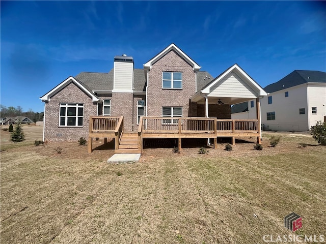 back of property with a wooden deck, ceiling fan, and a lawn