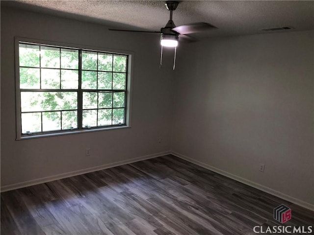 empty room featuring ceiling fan, dark hardwood / wood-style floors, and a textured ceiling