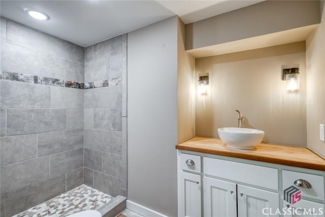 bathroom with tiled shower and vanity