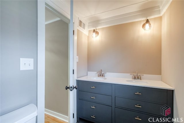 bathroom with vanity, toilet, crown molding, and wood-type flooring