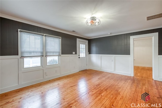 spare room featuring ornamental molding and light wood-type flooring