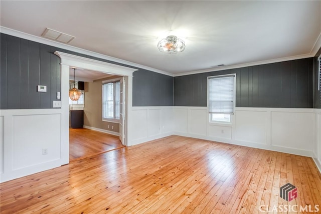 spare room featuring ornamental molding and light hardwood / wood-style floors