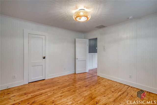 empty room with light wood-type flooring and ornamental molding