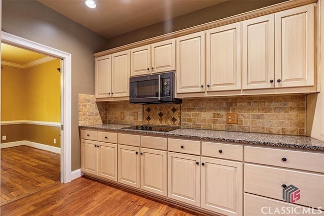 kitchen with black appliances, tasteful backsplash, dark stone counters, and light hardwood / wood-style flooring