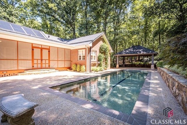 view of swimming pool featuring a sunroom, a gazebo, and a patio