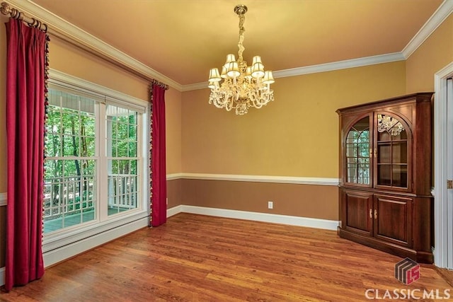 unfurnished dining area featuring crown molding, wood-type flooring, and a notable chandelier