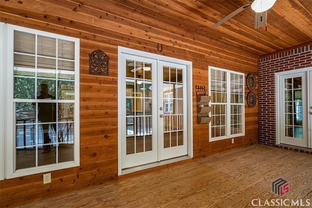 doorway featuring brick wall, french doors, wooden walls, ceiling fan, and wooden ceiling