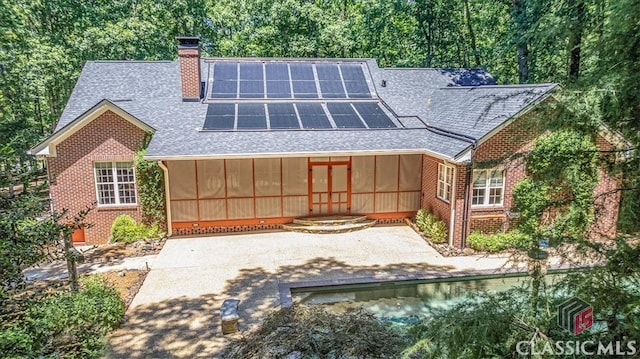 back of house featuring solar panels