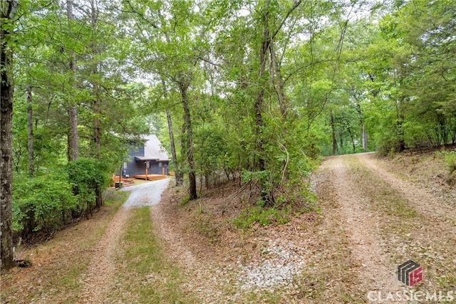 view of street with driveway and a forest view