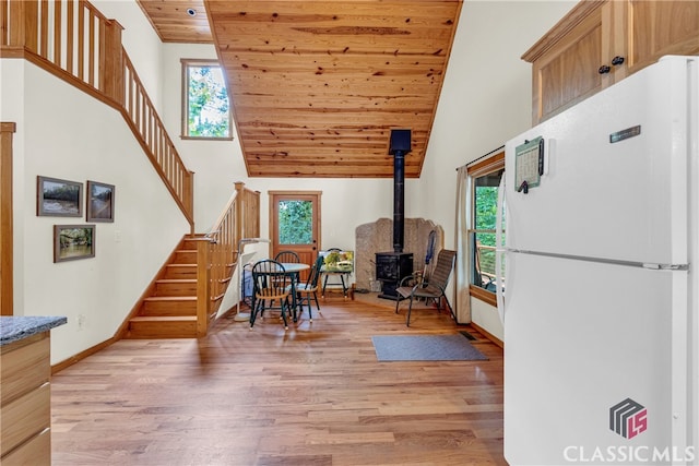 living area featuring a wood stove, high vaulted ceiling, wooden ceiling, and a wealth of natural light