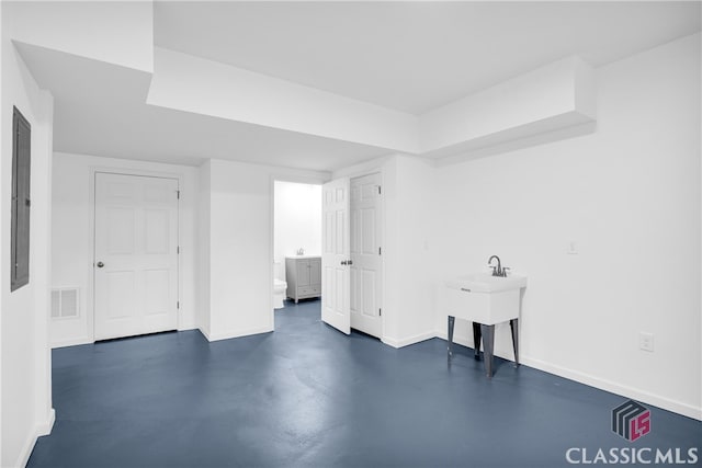 interior space featuring finished concrete flooring, visible vents, electric panel, and baseboards