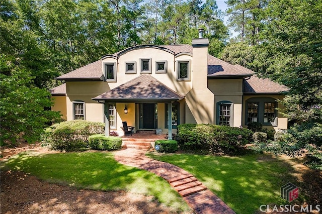 french country home featuring covered porch and a front yard