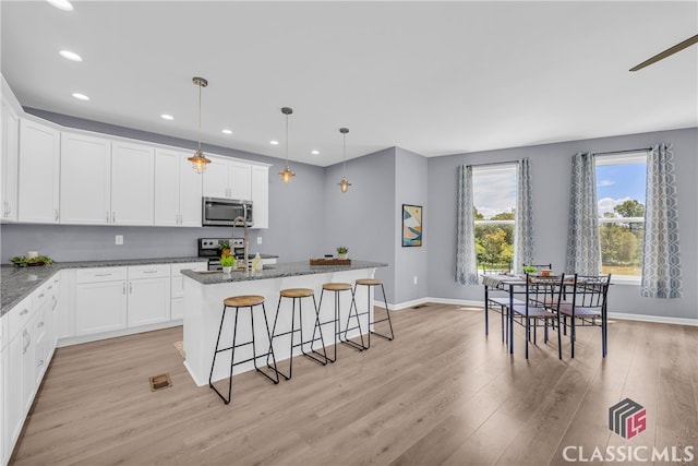 kitchen featuring dark stone counters, white cabinetry, light hardwood / wood-style flooring, and stainless steel appliances