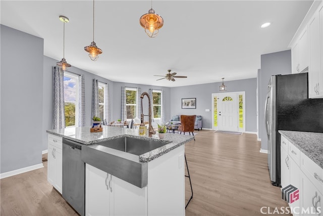 kitchen featuring white cabinets, a kitchen bar, a center island with sink, and stainless steel appliances