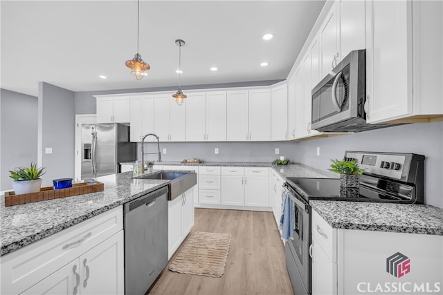 kitchen featuring white cabinetry, sink, stainless steel appliances, light hardwood / wood-style flooring, and pendant lighting