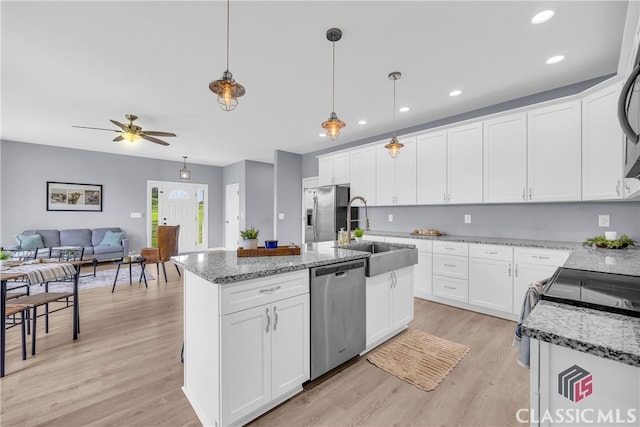 kitchen featuring pendant lighting, white cabinetry, stainless steel appliances, and an island with sink