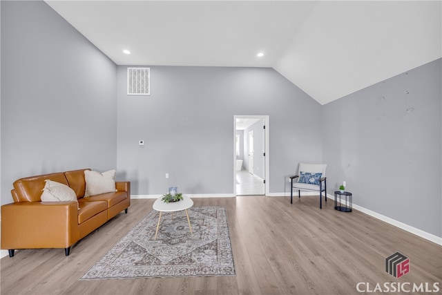 living room with light wood-type flooring and vaulted ceiling