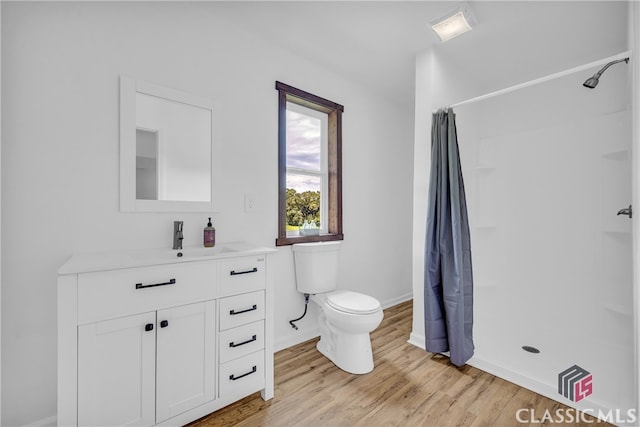 bathroom featuring hardwood / wood-style floors, a shower with curtain, toilet, and vanity