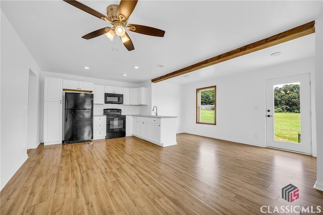 unfurnished living room featuring beamed ceiling, a healthy amount of sunlight, and light hardwood / wood-style floors