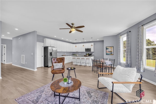 living room featuring ceiling fan, sink, and light hardwood / wood-style flooring