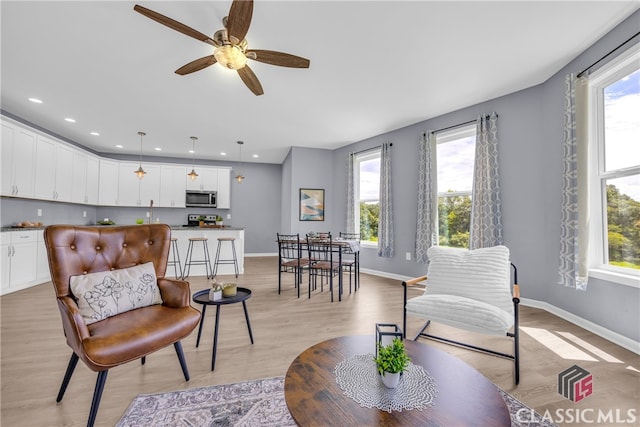 living room with ceiling fan, light hardwood / wood-style flooring, and a healthy amount of sunlight