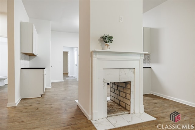 unfurnished living room featuring baseboards, light wood finished floors, and a premium fireplace