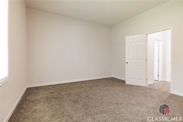 empty room with vaulted ceiling and carpet flooring