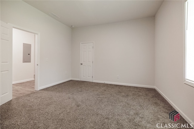 spare room featuring visible vents, carpet, electric panel, and baseboards