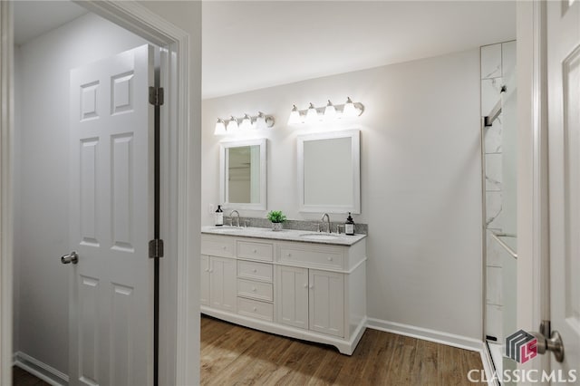 bathroom featuring double vanity, a sink, baseboards, and wood finished floors