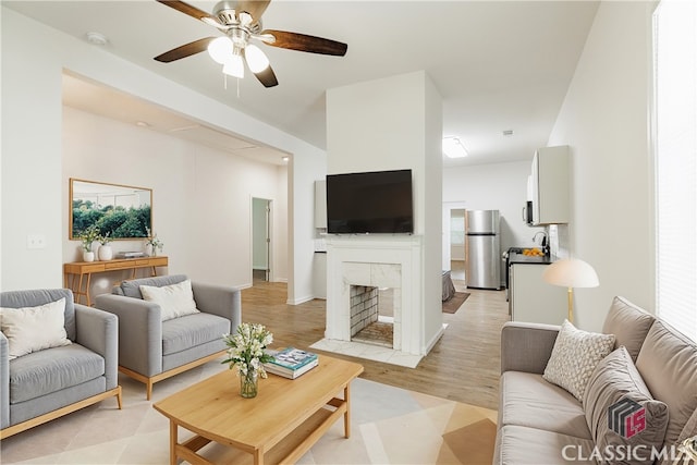 living room featuring ceiling fan, light hardwood / wood-style flooring, and a premium fireplace