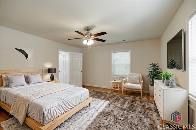 bedroom featuring baseboards, ceiling fan, visible vents, and wood finished floors