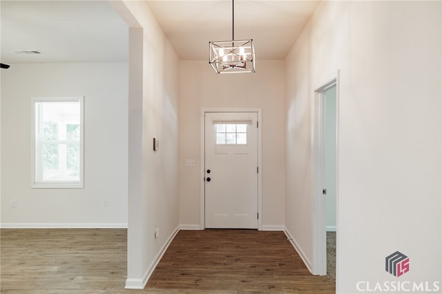 entryway with an inviting chandelier, baseboards, visible vents, and wood finished floors