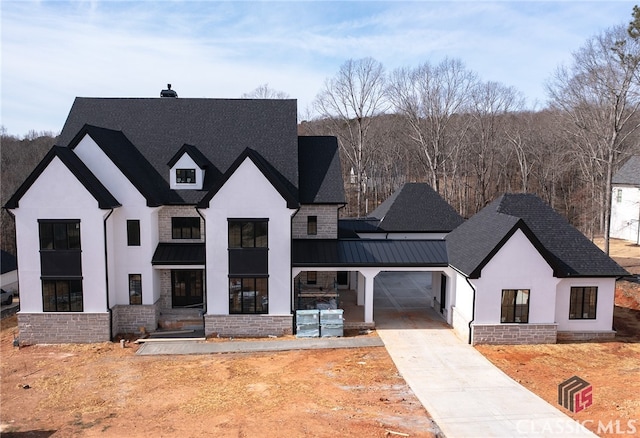 view of front of house featuring driveway, a standing seam roof, a garage, and metal roof