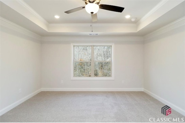 unfurnished room featuring ornamental molding, a tray ceiling, and light carpet