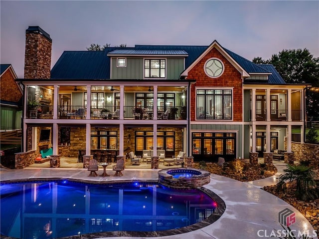 back house at dusk with a patio area and a pool with hot tub