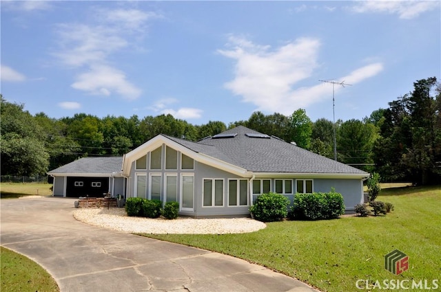 view of front of property featuring a garage, driveway, a front lawn, and stucco siding