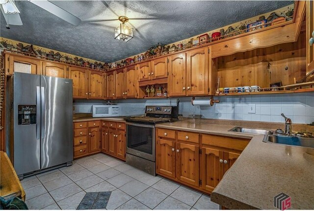 kitchen featuring tasteful backsplash, light tile patterned floors, sink, ceiling fan, and appliances with stainless steel finishes