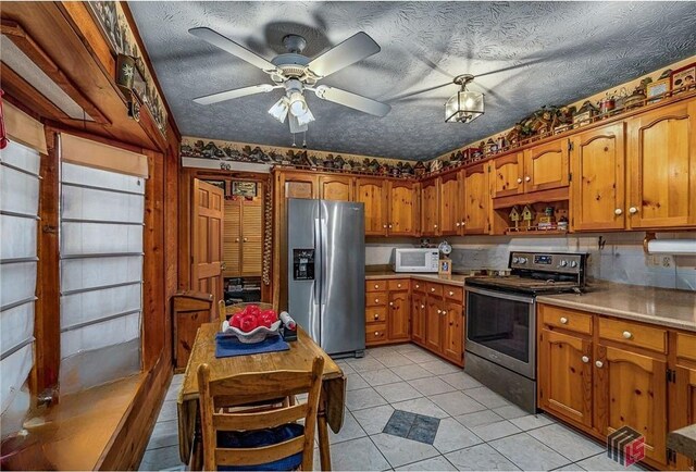 kitchen with backsplash, light tile patterned floors, stainless steel appliances, ceiling fan, and a textured ceiling