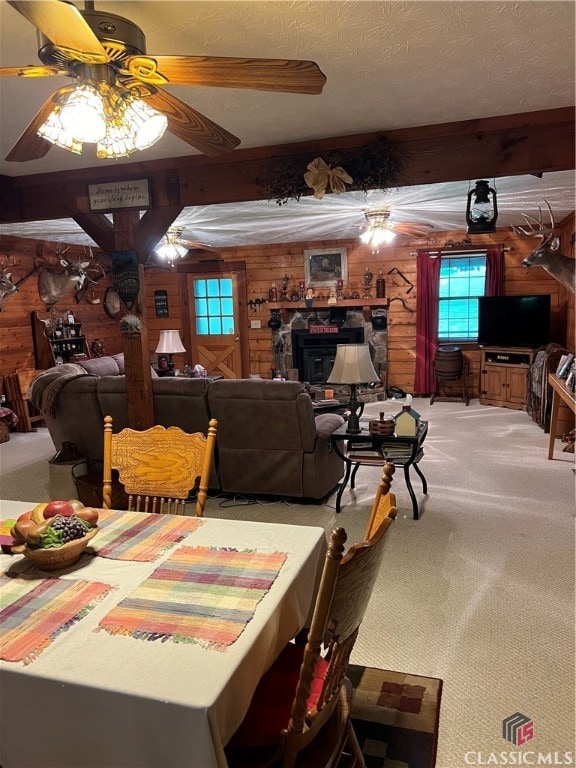 dining space featuring a textured ceiling, beam ceiling, ceiling fan, and carpet